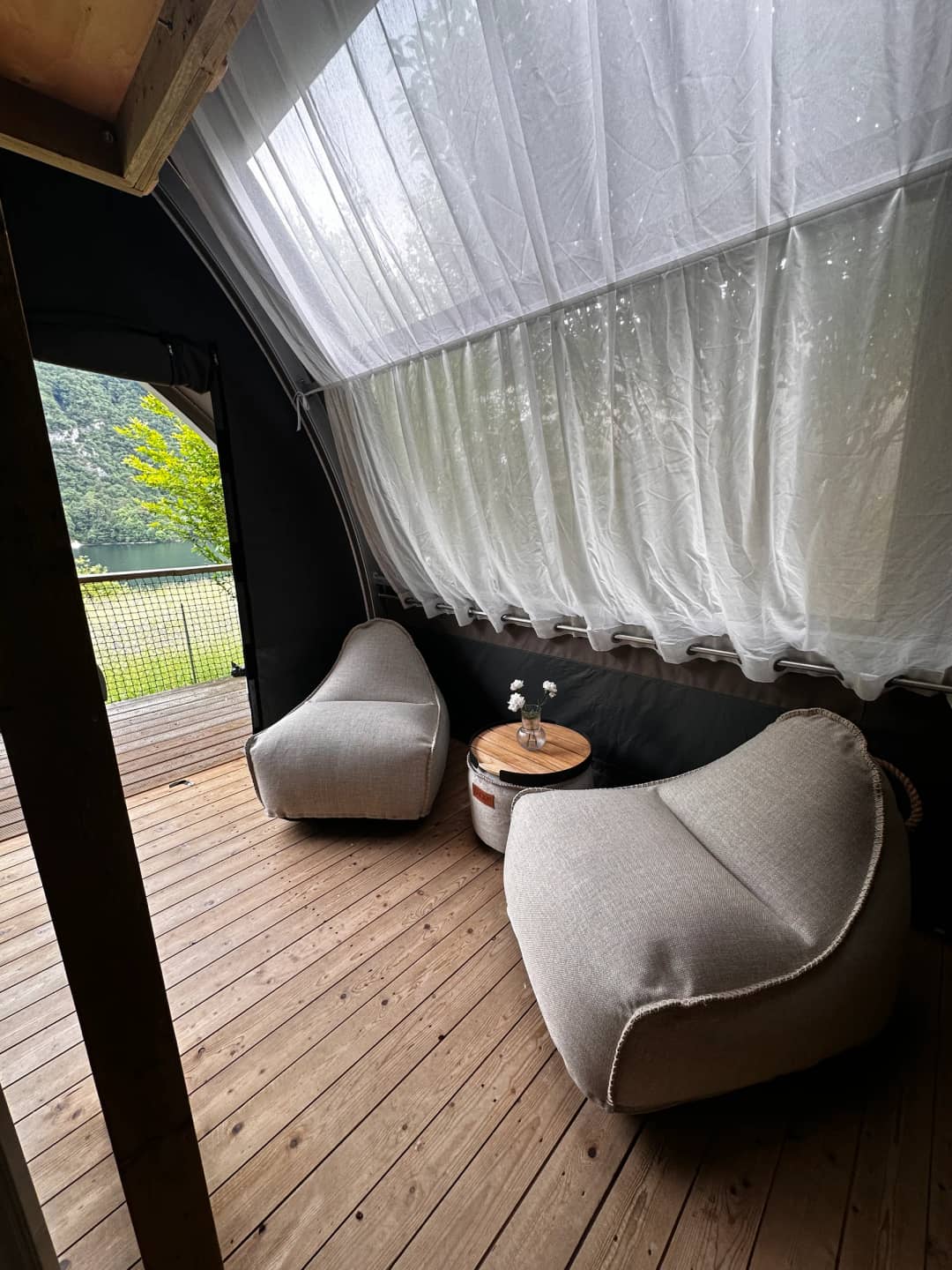 Sitzecke mit Hockern unter dem hellen Vorhang in der Big Oak Lodge XS