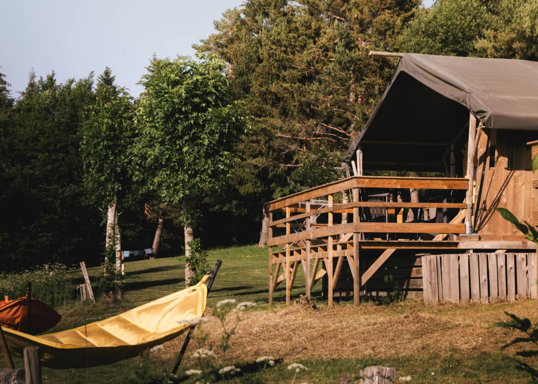 Base Lodge mit Holzterrasse und Hängematte zwischen den Bäumen